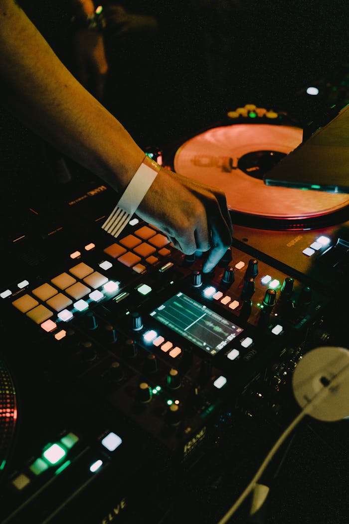 Close-up of a DJ's hand on a mixer, adjusting controls during a live performance.